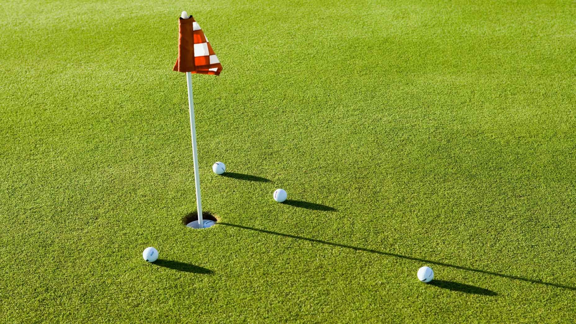 Golf balls around the flag on a sunlit putting green